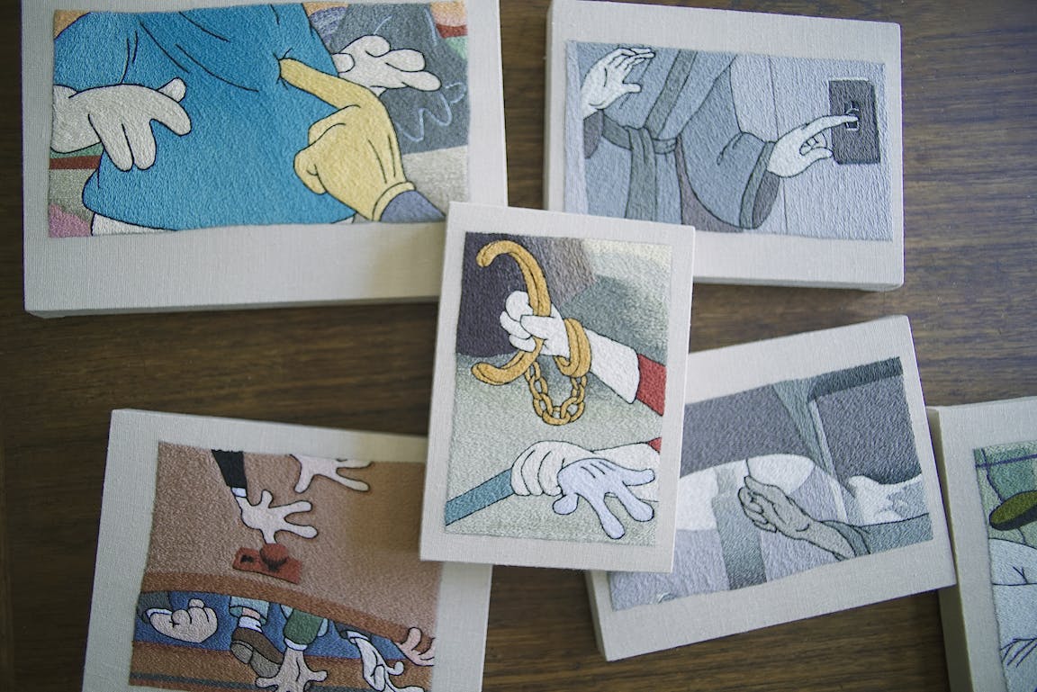 Six cartoonish embroideries are scattered on a desk.